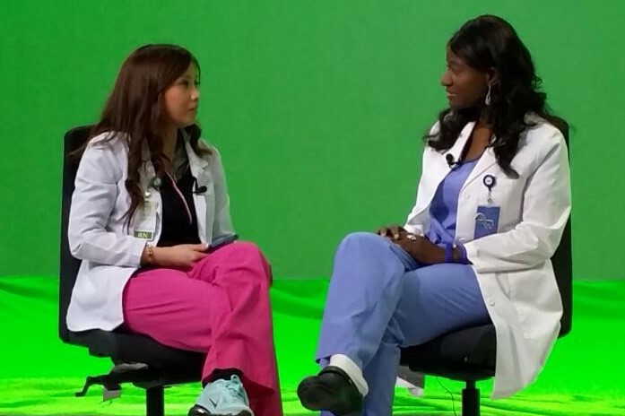 Sonya Justice and another nurse sitting in front of a green screen.